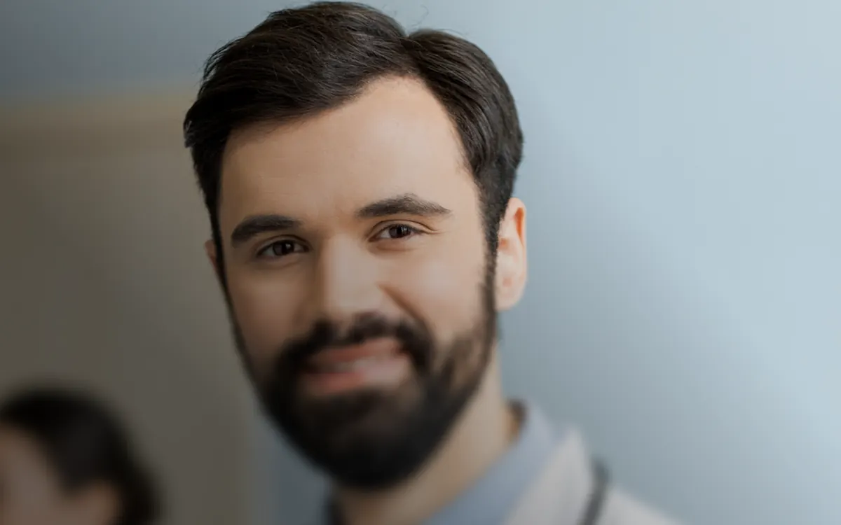 Médico de jaleco sorrindo no consultório