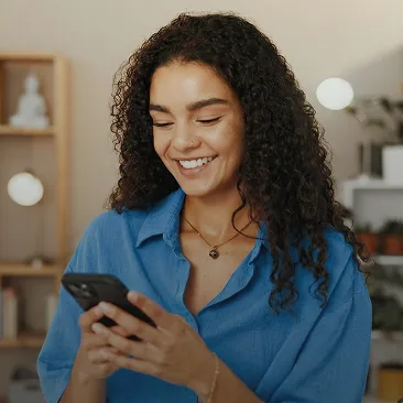 Mulher sorrindo enquanto usa o celular em casa